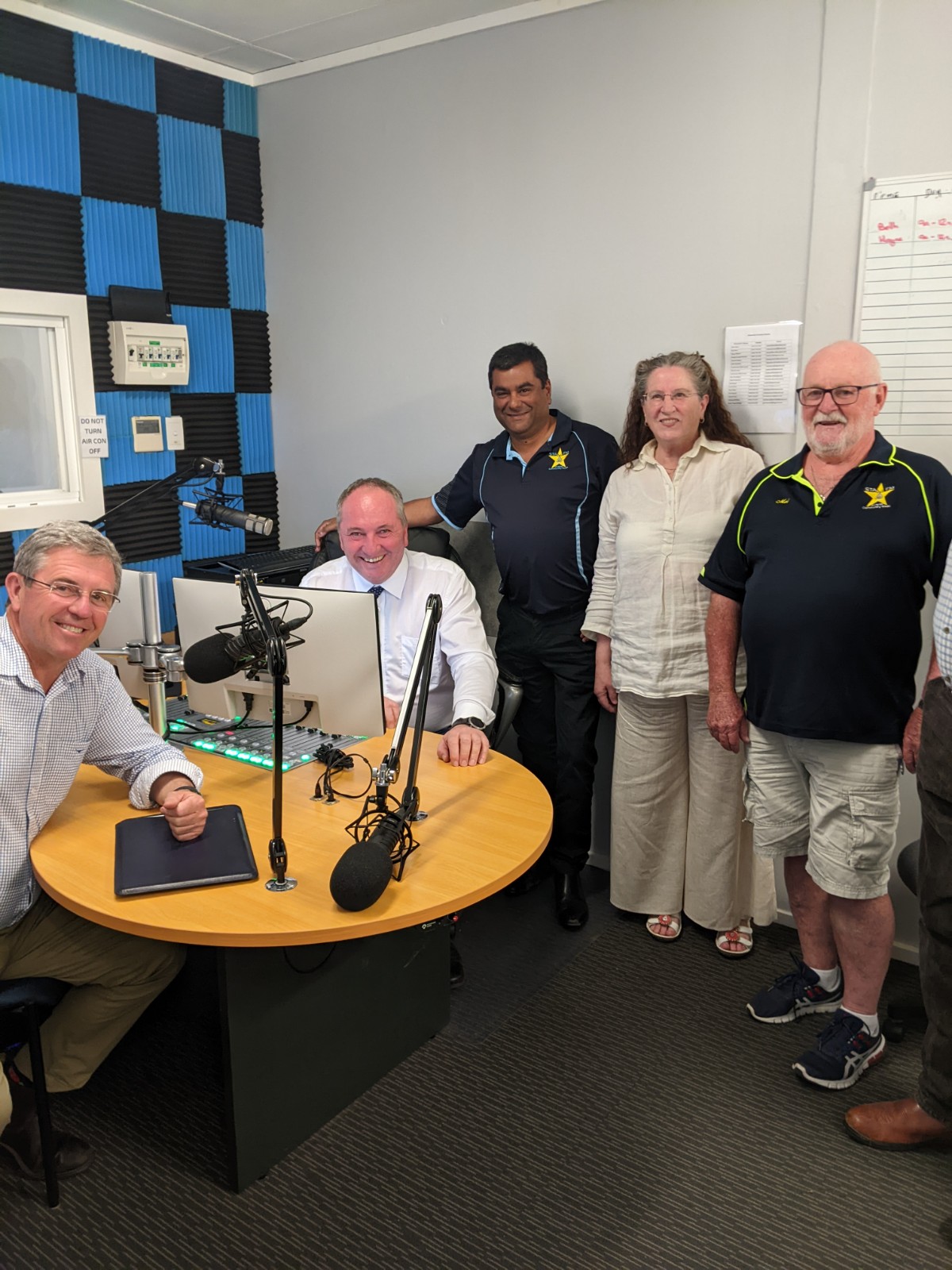 A photo of Barnaby Joyce and David Gillespie sitting at the studio desk with Sta FM workers standing beside them